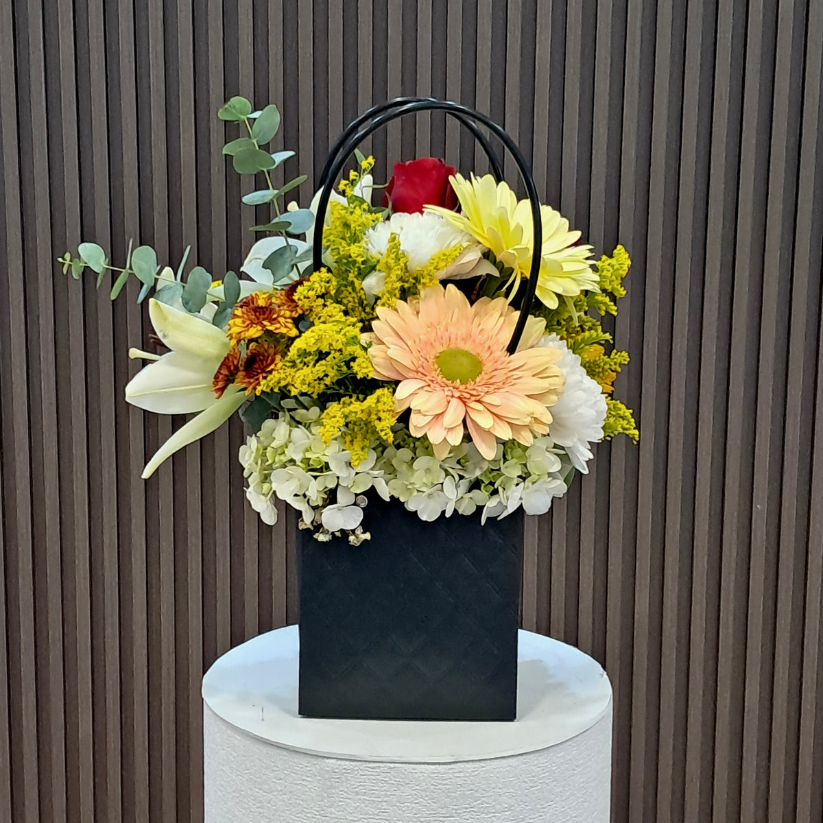 Vista lateral de Primavera de Gala con gerbera, lirios y pomas, disponible en Velve Floristería, Paseo de las Flores.