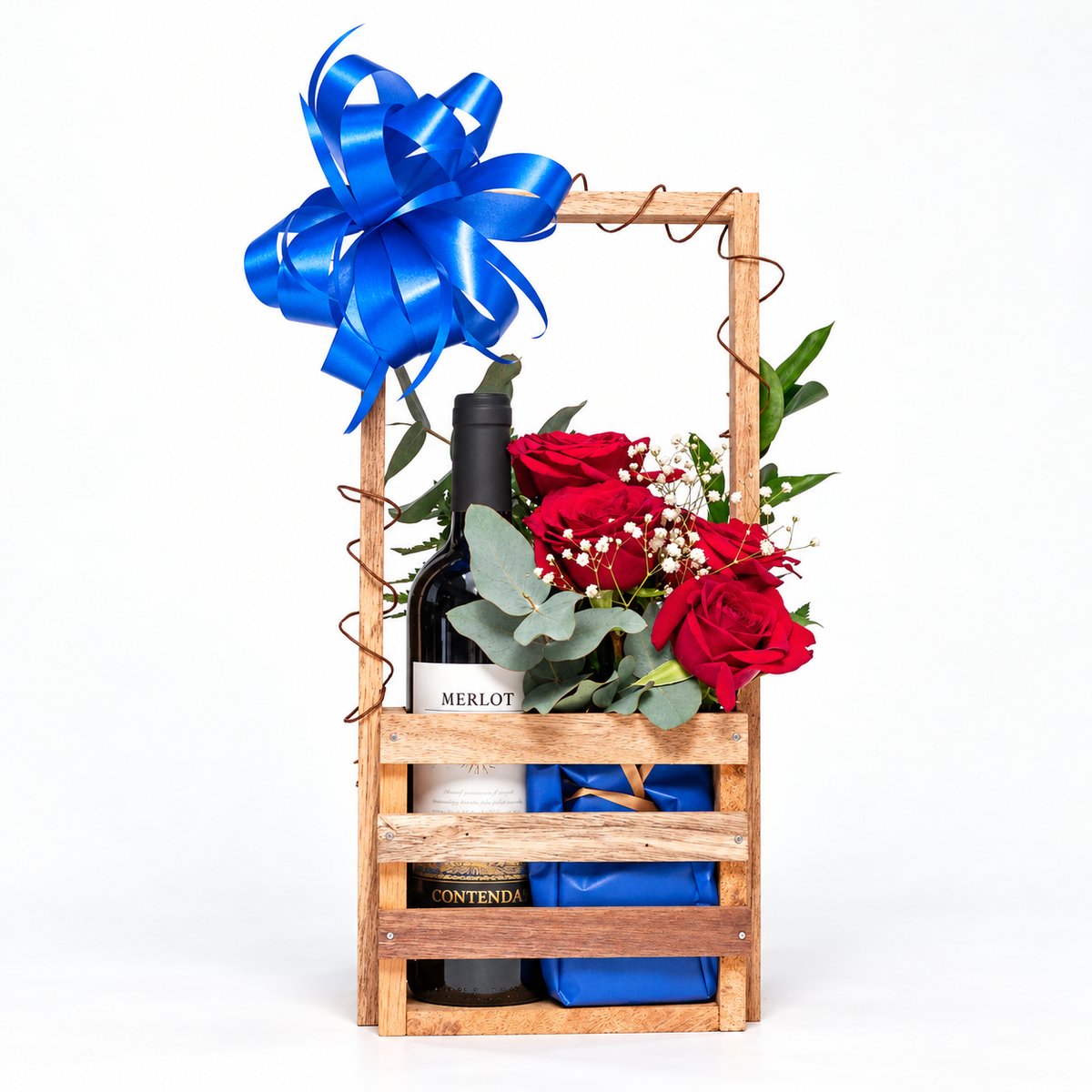 Canasta de madera con vino Merlot, rosas rojas y paquete de regalo azul, vista completa. Velve Floristería, Paseo de las Flores, Heredia.