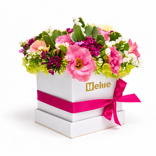 Lisianthus rosados, flores blancas y moradas en caja de madera blanca con lazo fucsia. Velve Floristería, Heredia.