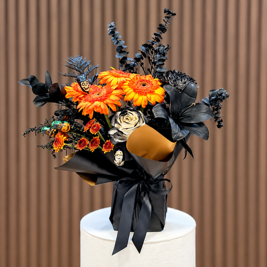 Ramo de Halloween con gerberas naranjas, rosa blanca con detalles negros y lazo negro, vista diagonal. Velve Floristería, Paseo de las Flores, Heredia.