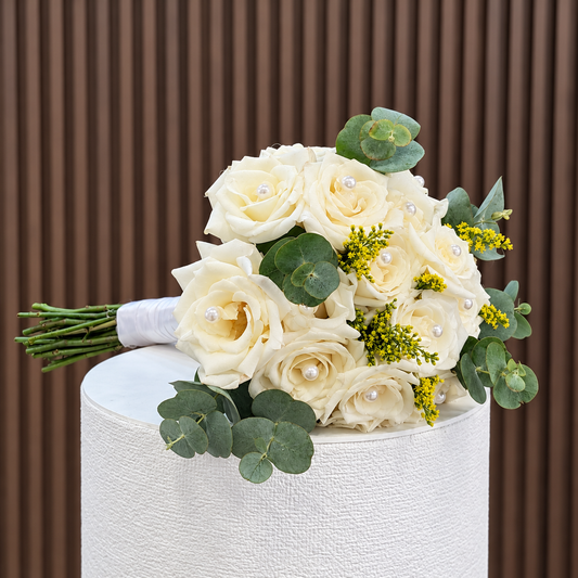 vista lateral de bouquet de rosas blancas con perlas eucalipto solidago y mango de saten blanco velve floristeria paseo de las flores heredia