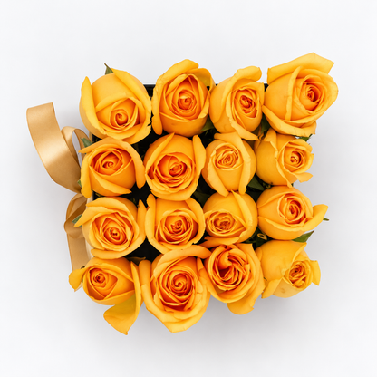 Vista superior de dieciséis rosas amarillas en caja negra con lazo dorado. Velve Floristería, Paseo de las Flores, Heredia.